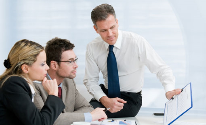 businessman showing clipboard to man and woman